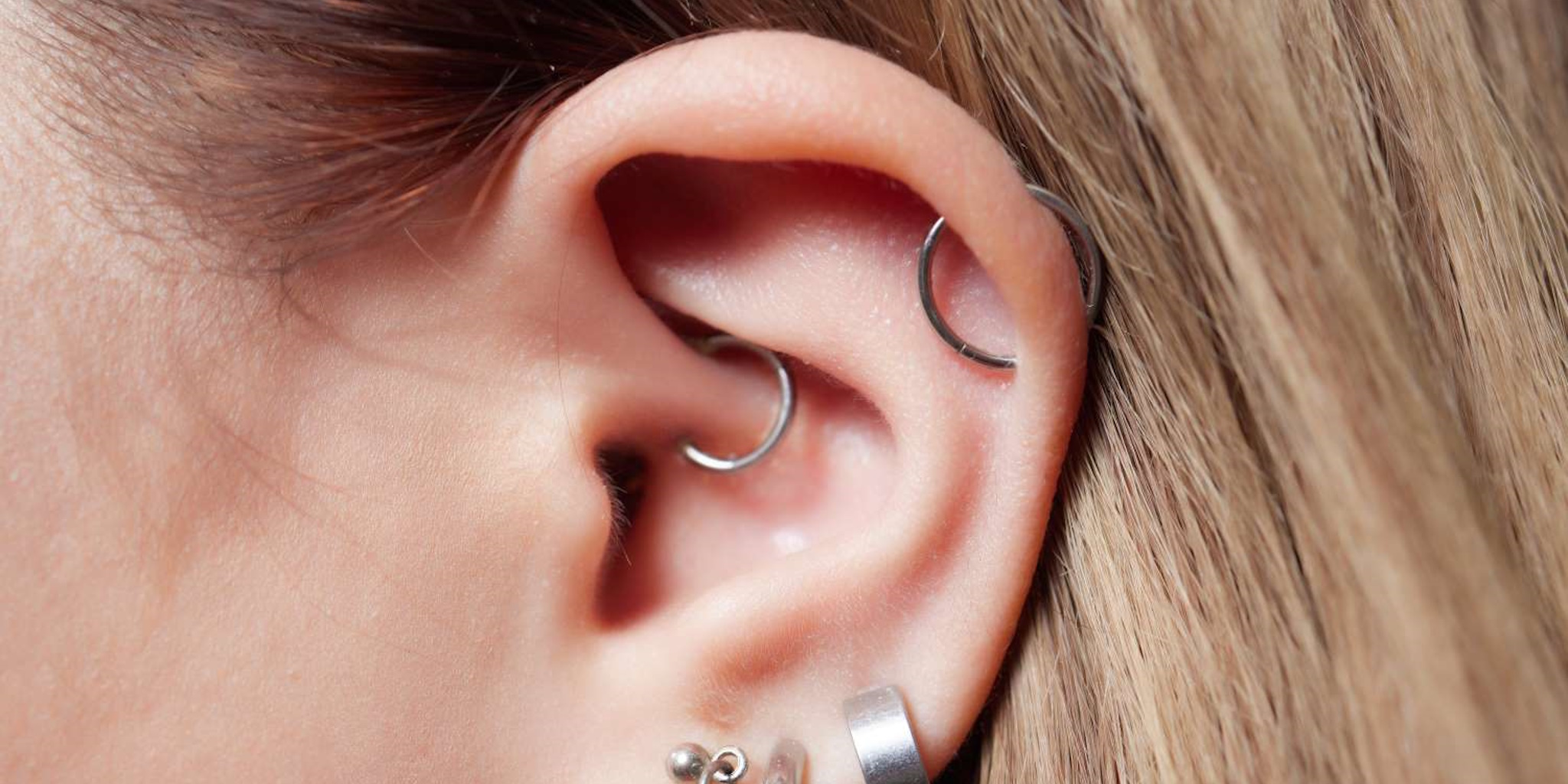 A female with long blond hair that has a daith piercing in her ear.