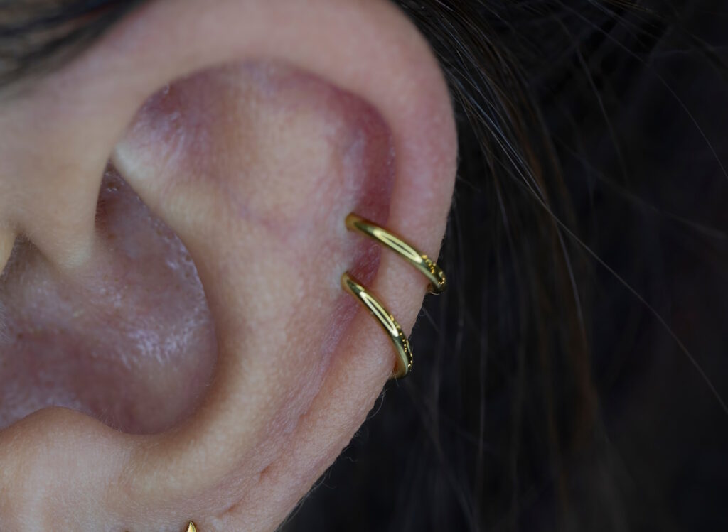 A double helix with gold hoops shown in the ear of a long hair woman.