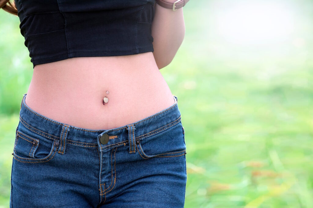 A woman in a crop top showing off her belly button body piercing.