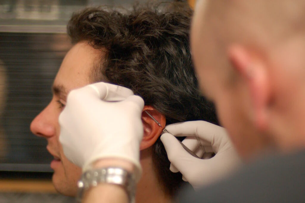A man getting a piercing by a piercer.