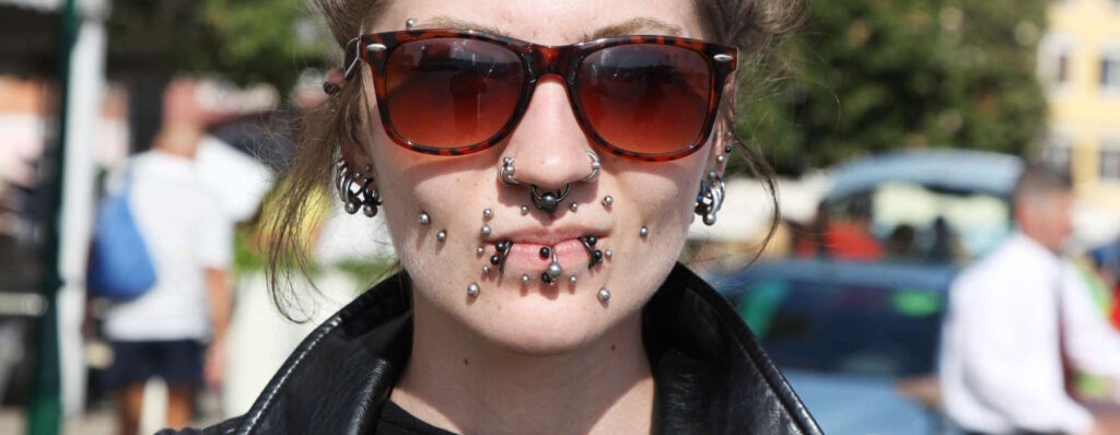 A female with multiple face piercings.