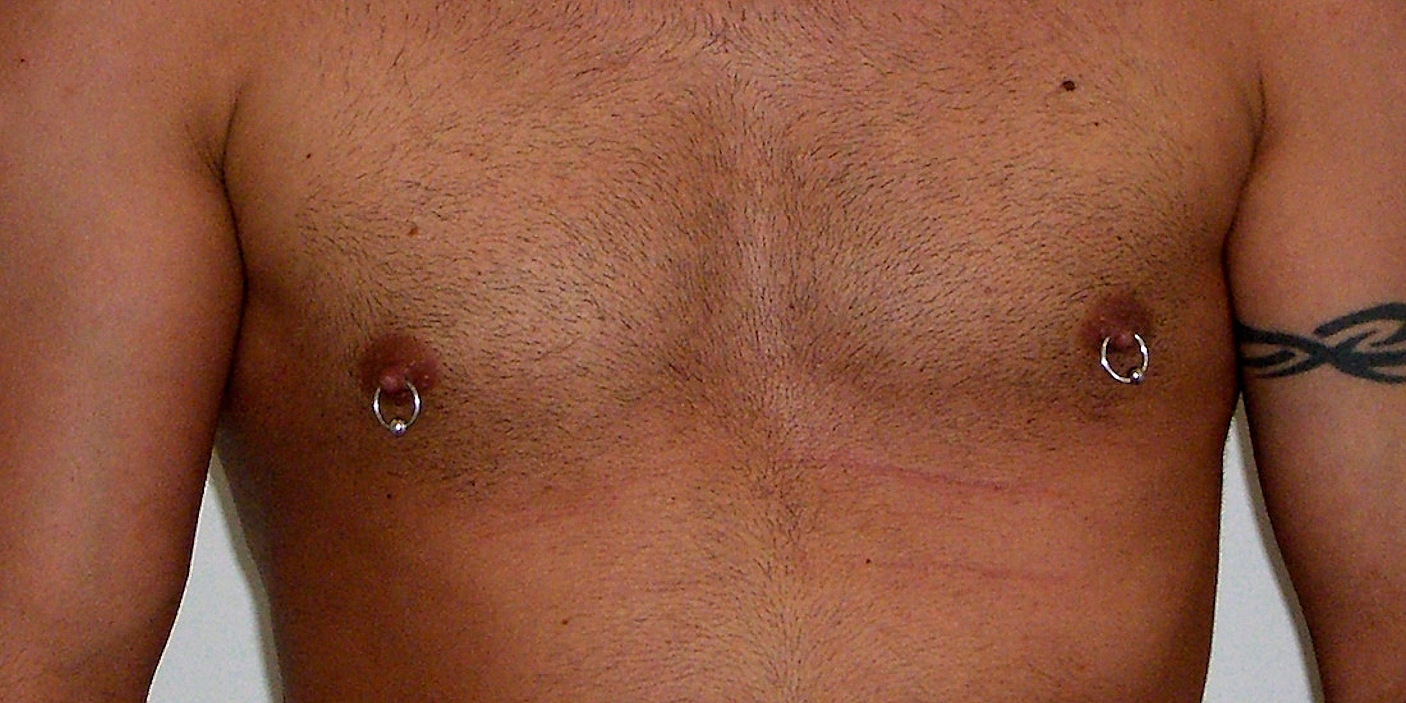 The check of a man with a nipple piercing on each of his nipples.