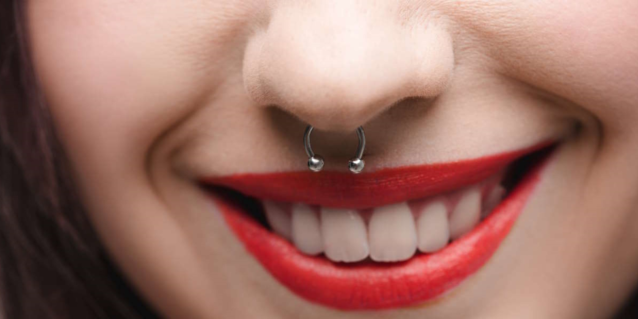 A septum piercing on a female with red lipstick.