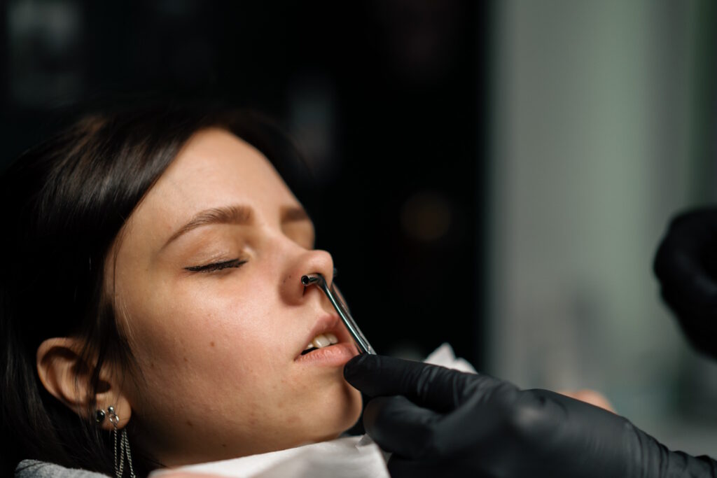 A woman with piercing clamps in her nose.