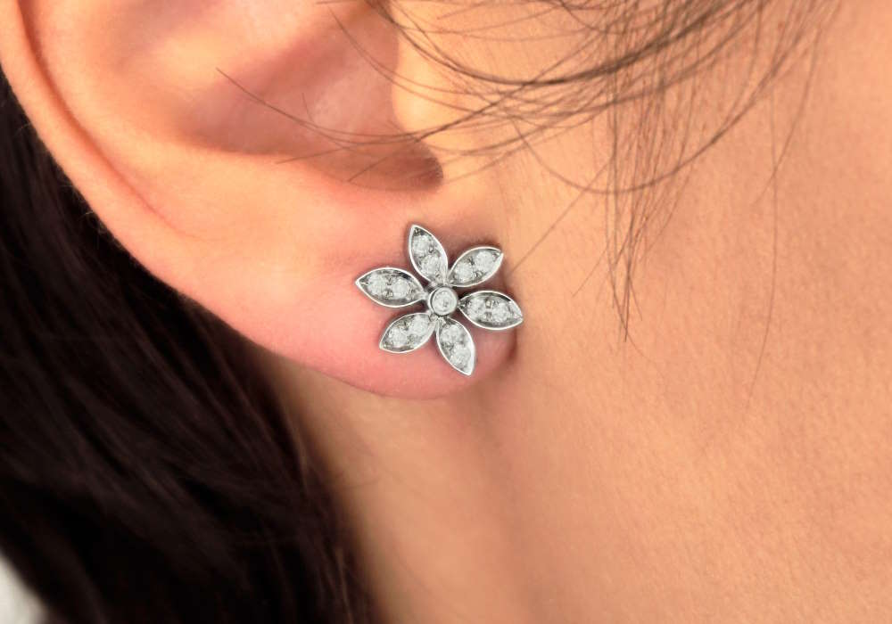 A woman with a beautiful flower design earring in it.