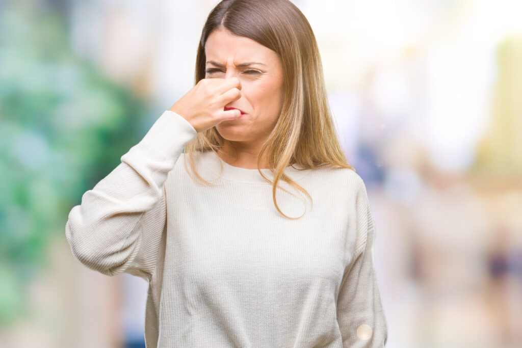 A woman pinching her nose trying to figure out why her nose piercing smells.