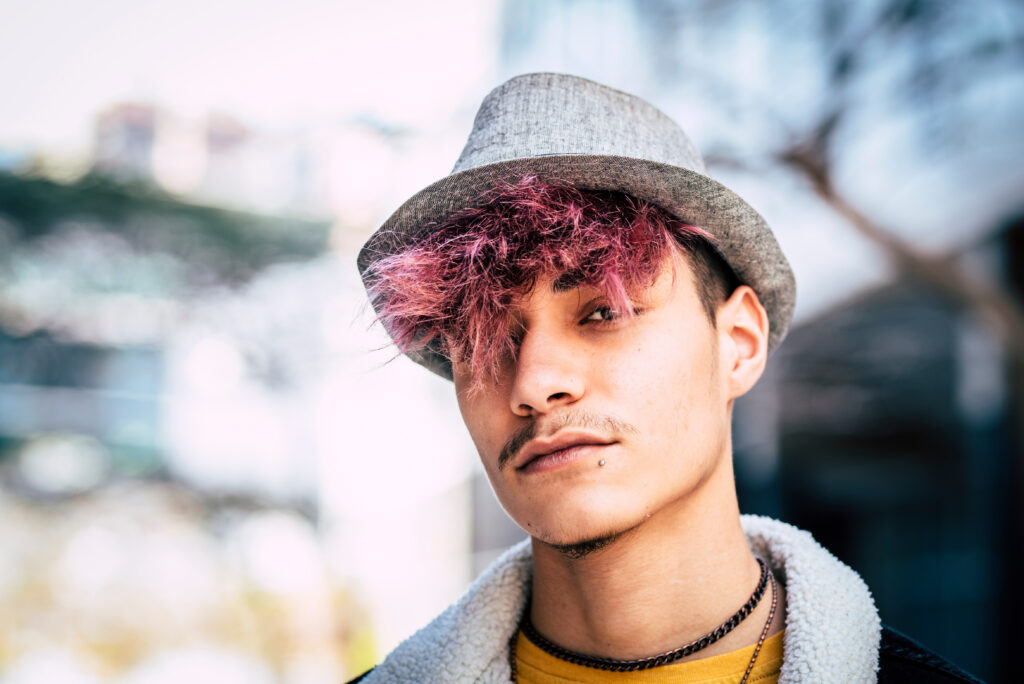 An urban male with purple hair with a hat on.