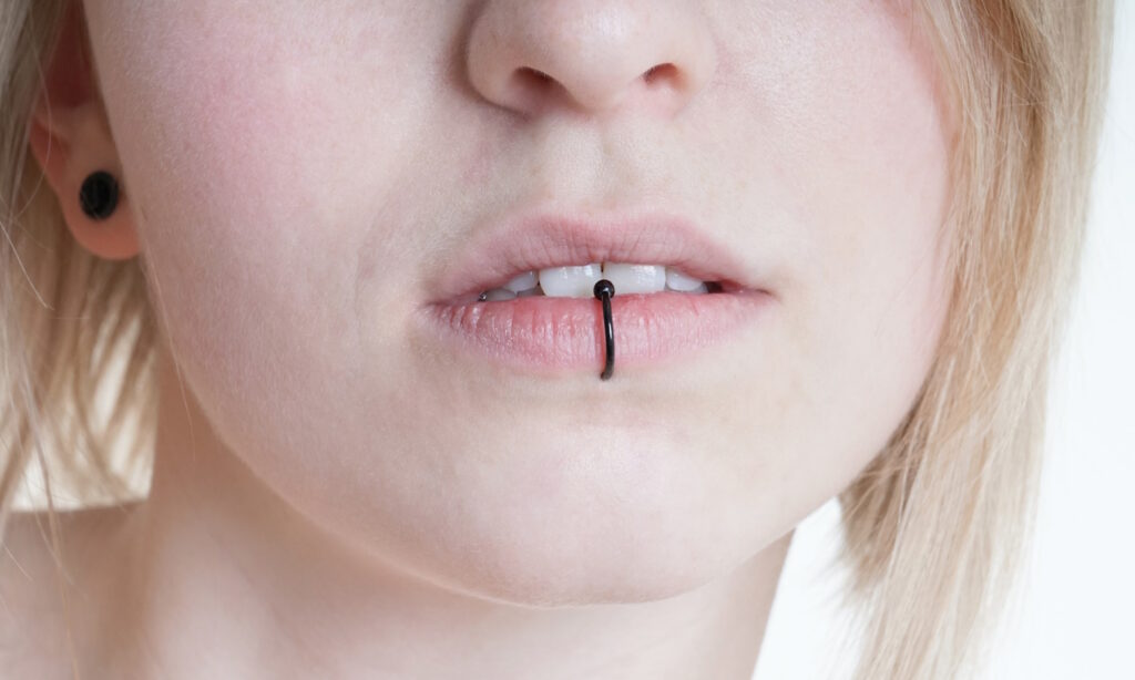 A female with a black captive bead ring in her labret piercing.