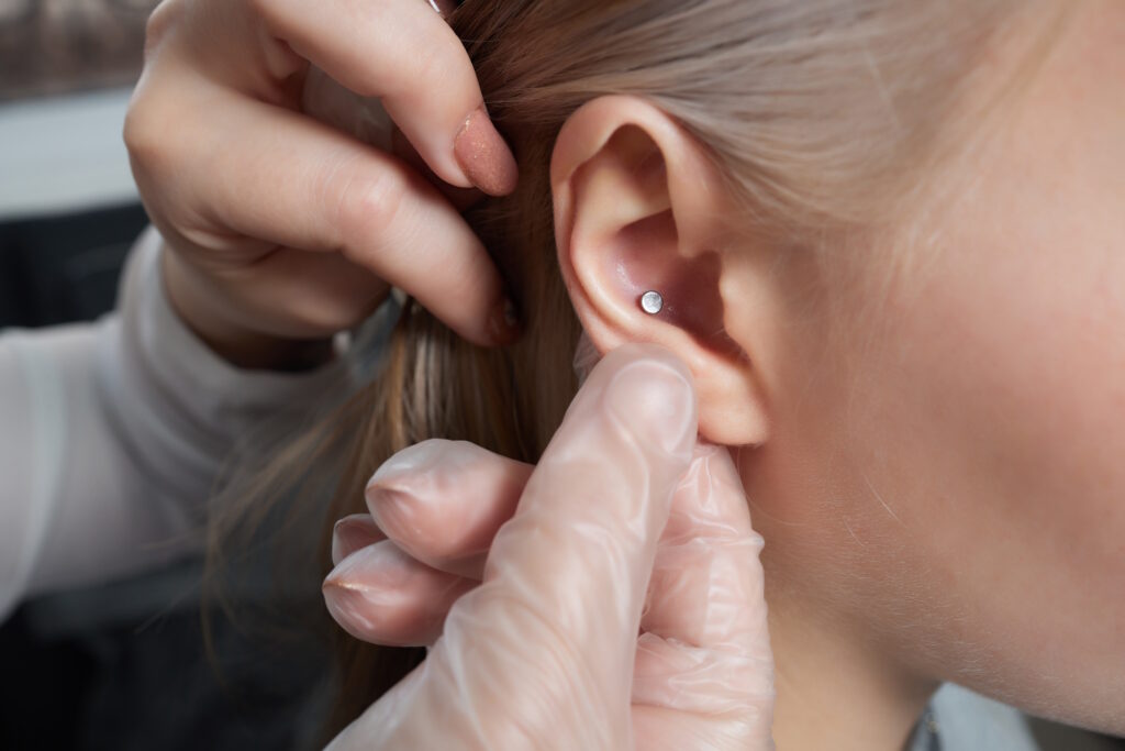 A piercer holding the ear of a woman to show off her fresh conch.