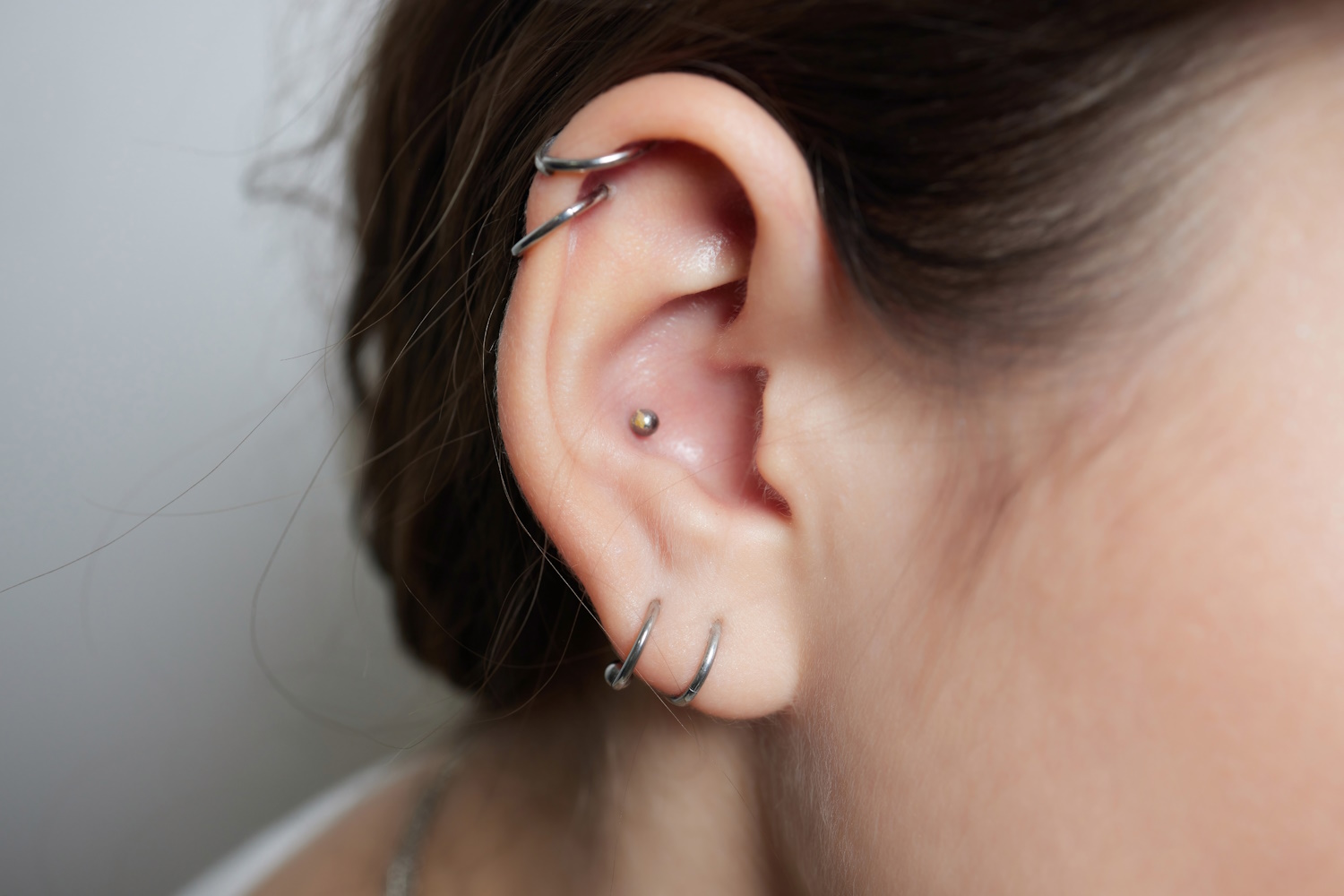 A woman with a couple earlobe piercings, a couple helix piercings, and an inner conch piercing.