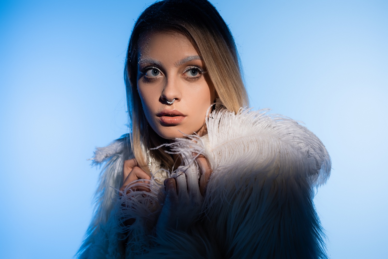 A young woman in a jacket with a septum piercing.