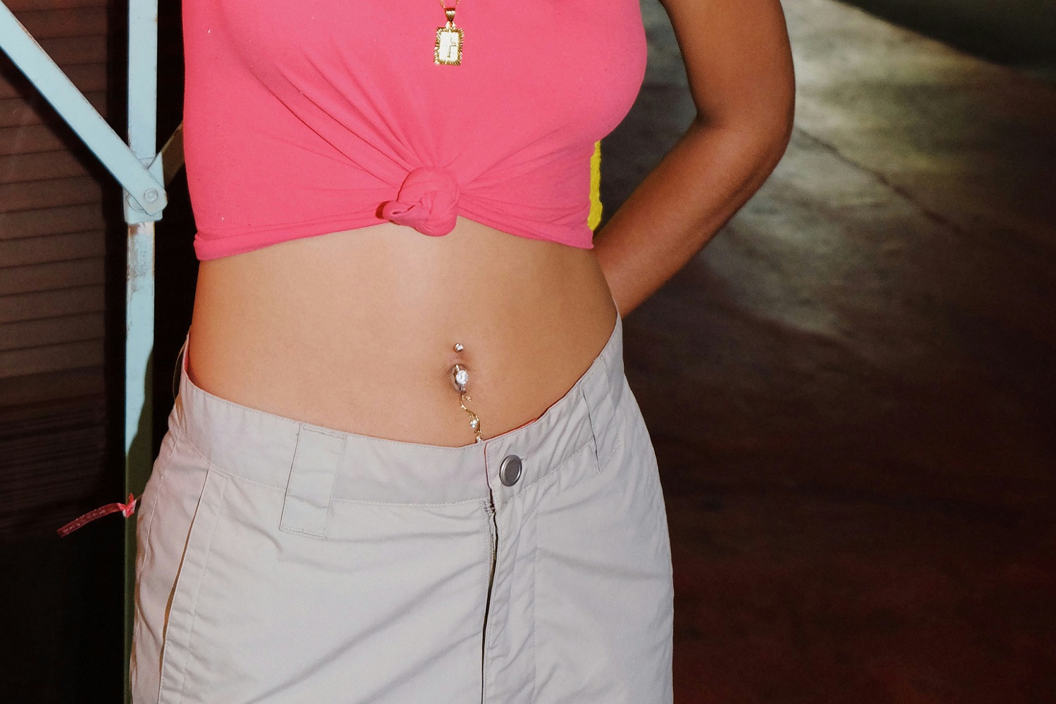 A woman with a pink crop top showing off her belly button piercing.